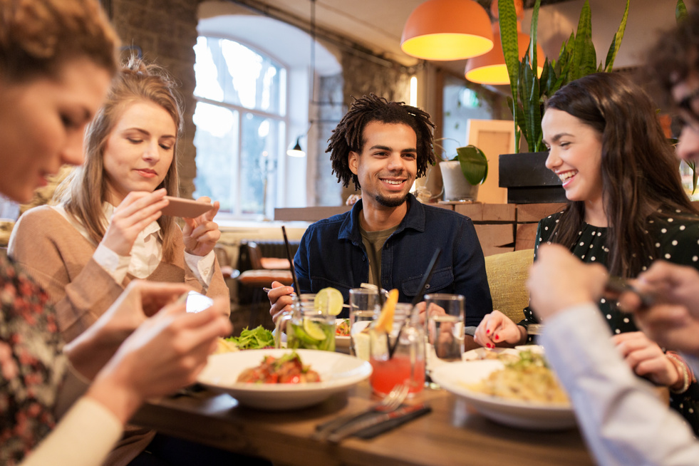 Friends with Smartphones Eating at Restaurant