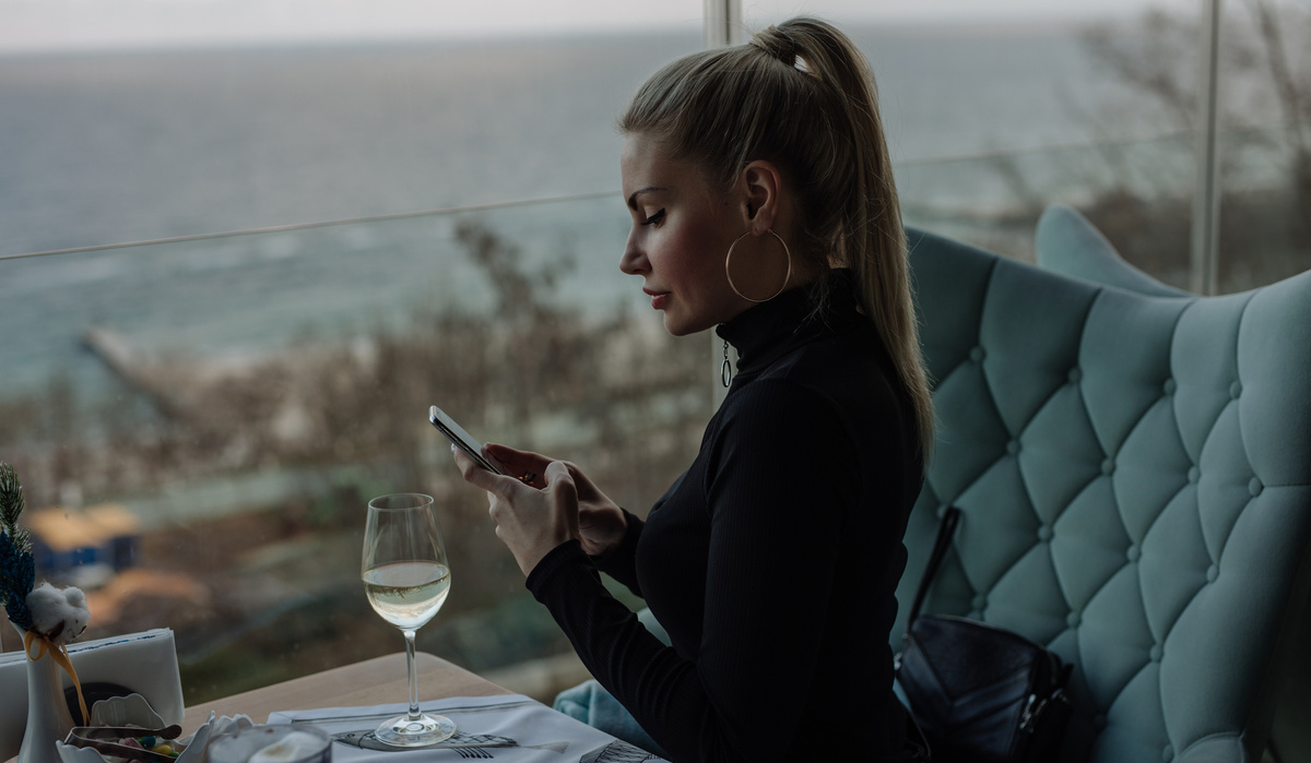 Luxury woman using phone in restaurant with sea view